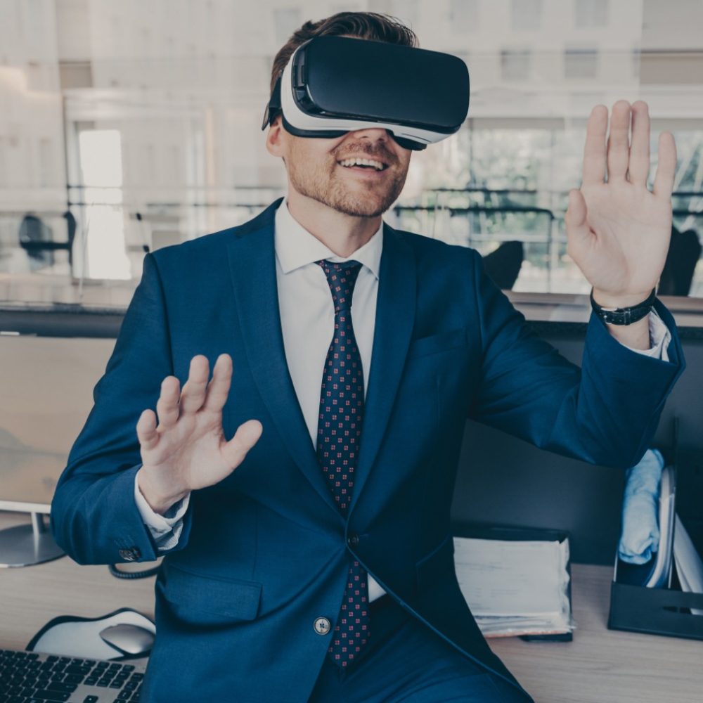 Excited entrepreneur in virtual reality glasses touching objects interact with 3D simulation, smiling male in VR goggles have fun testing new device while working in office, digital technology concept